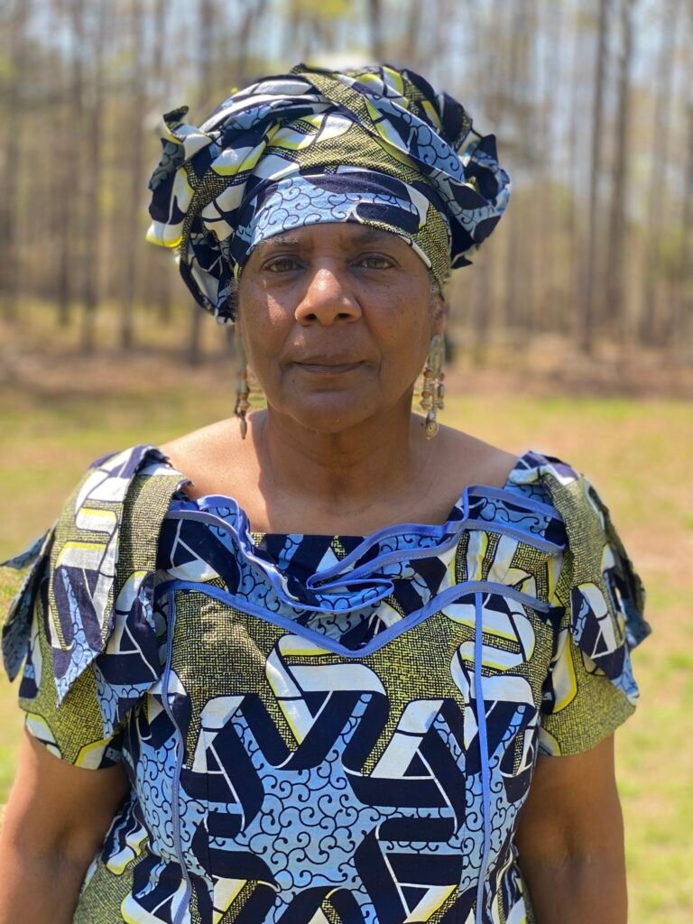 a woman dressed in African garb standing outside