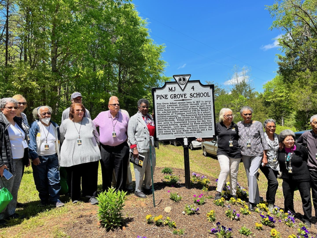 people gather outside around a grounds marker